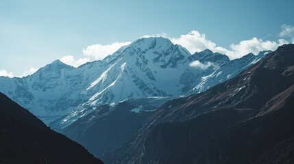 Obraz premium Majestic snow-capped peaks rise above a dramatic mountain range, showcasing a serene and vast landscape under a clear sky.