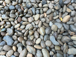 Close up texture of assorted smooth round river pebbles in earthy grey brown and tan colors