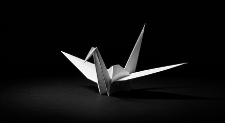 Elegant origami paper crane sculpture isolated on a dark black background