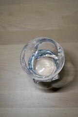 A small transparent glass bowl is placed carefully on a wooden table