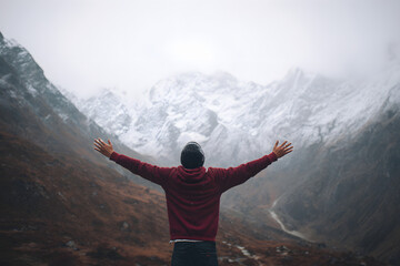 Man with arms wide open facing snowy mountains. Lifestyle image symbolizing freedom and adventure