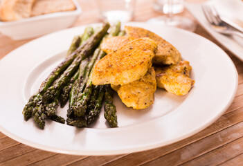 fried chicken breast pieces with asparagus on white plate