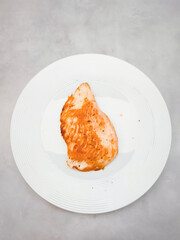 Grilled chicken breast on white plate, healthy eating promoting wellness