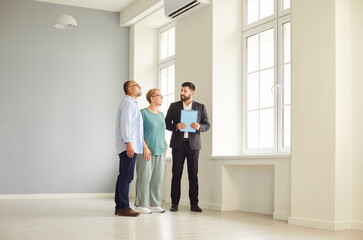 Realtor and agent guide a senior couple through new apartment during a tour and viewing, helping buyers assess the interior and showing key home features. Real estate market and buying property.