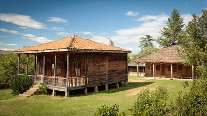 Panoramic view of traditional Georgian houses with tile and thatched roofs, surrounded by nature. Peaceful rural lifestyle