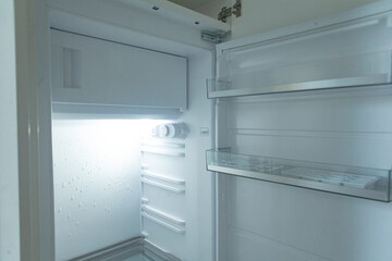The image depicts the interior of a completely empty refrigerator featuring neatly arranged shelves...