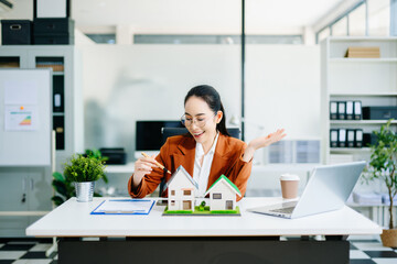 Confident real estate agent presenting house models in office. Perfect for property, mortgage,...