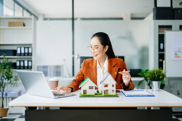 Confident real estate agent presenting house models in office. Perfect for property, mortgage,...