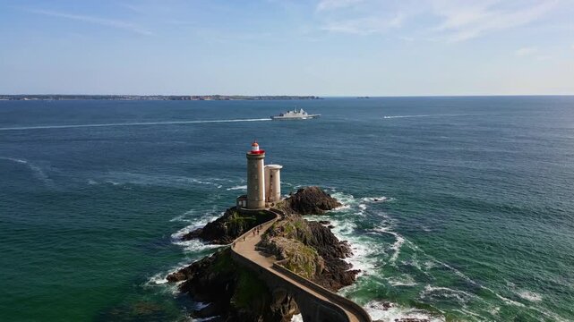 Petit Minou Lighthouse with warship in background, France. Aerial forward, Plouzan&eacute;, Brittany, France