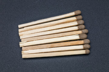 Pile of wooden matchsticks on a dark, textured background, representing fire and ideas