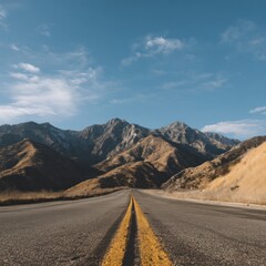Fototapeta premium Scenic highway leading to majestic mountains under a tranquil blue sky