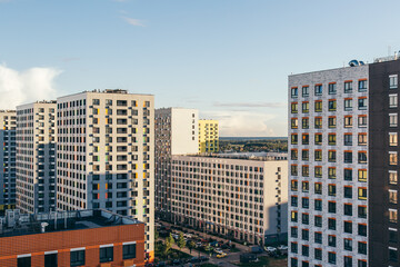Naklejka premium Modern residential complex with tall apartment buildings and colorful facades under clear evening sky, concept of urban lifestyle, real estate rent and property investment