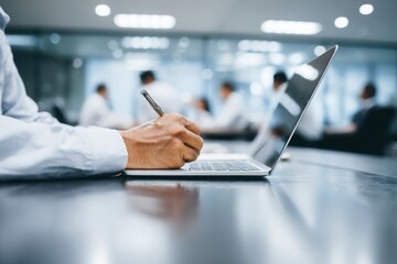 Fototapeta premium a businessman in a shirt is working on a laptop computer he taking notes or participating in a meeting in a conference room, using the laptop for a financial concept. the background is blurred.
