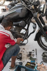 Mechanic repairing motorcycle engine in workshop