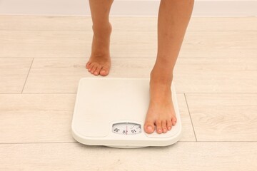 Little boy standing on scales indoors, closeup