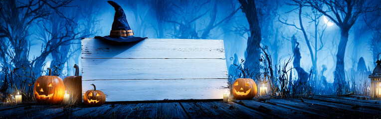 White Wooden Sign with Black Witch Hat and Glowing Orange Pumpkins in Dark Forest with Blue Moonlit Sky and Bare Trees in Background
