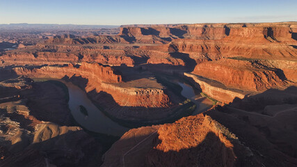 Aerial view of the Colorado River carving its path through the red rock canyons, revealing a stunning contrast between water and stone, Moab, Utah, United States.