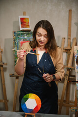  Teacher learn children to draw pictures in an art lesson. Artist explains how to mix and combine colors. Childs painting in workshop. Kids drawing brush on easel. Education, learning concept.