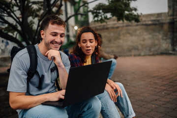 Students working on laptop outdoors, sharing ideas and learning together