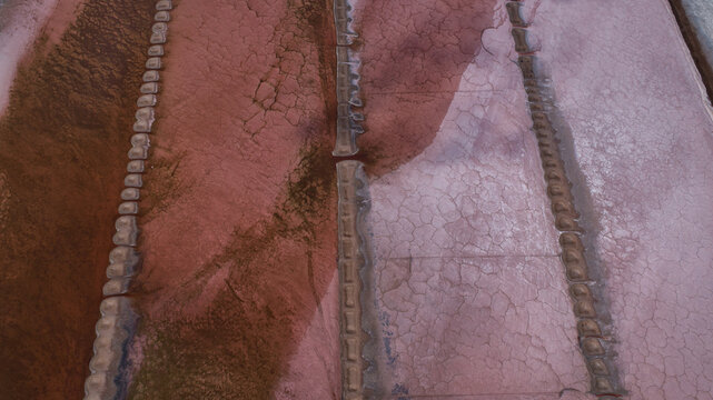 Aerial view of the textured earth, divided into geometric shapes by raised barriers, displays a striking palette of pinks and browns, creating an abstract landscape., Location Omitted.