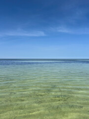 Bright turquoise water stretches across the beach in Djerba, Tunisia. The serene atmosphere invites visitors to relax under the clear blue sky.