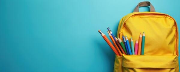 School supplies in yellow backpack on blue background. Colorful pencils, pens in bag. Back to school concept. Education banner with copy space, text space. Preparing student for study. Flat lay