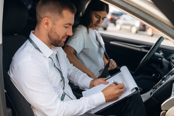 Side view. Woman is with instructor in car, driving school concept