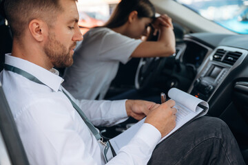 Obraz premium Disappointed, failure. Woman is with instructor in car, driving school concept