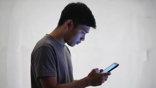 A man looking at a smartphone, seemingly engrossed in his device.