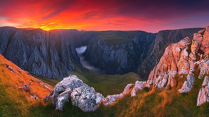 Mountain peaks glowing under sunrise sky, mist floating through valley