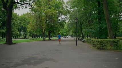 A man does push-ups and starts jogging in the park. A young athletic man exercises in the park in the morning.
