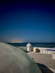 A serene scene unfolds on the roof of a white house in Djerba, Tunisia where stars twinkle brightly in the clear night sky, creating a tranquil ambiance.