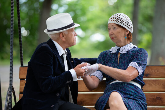 Elderly couple seated on a park bench sharing a heartfelt conversation in a serene outdoor setting during daytime - Powered by Adobe