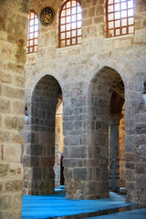 Historic stone arches illuminate the serene interior of a traditional Middle Eastern building during daylight hours