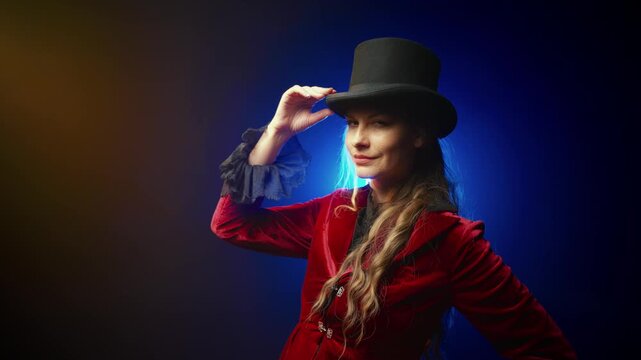 happy woman fashion model posing in black studio adjusting brim of top hat. fog dark city street night. Adult girl dressed in tailcoat frock coat suit classic bowler hat 1800s 1900s vintage old style