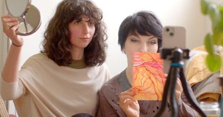 Two talented women collaborate artistically, creating captivating art and filming a video. One...