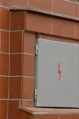 A grey electrical box securely mounted on a tiled wall, prominently featuring a bright red...