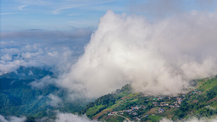 Aerial of Village in rain cloud cover tropical green mountain. Rainy season. Misty cover green forest. beautiful green village