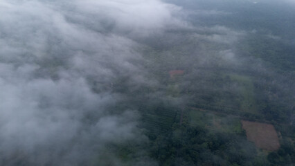 Aerial of Village in rain cloud cover tropical green mountain. Rainy season. Misty cover green forest. beautiful green village