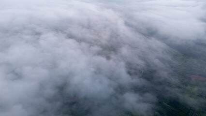 Obraz premium Aerial of Village in rain cloud cover tropical green mountain. Rainy season. Misty cover green forest. beautiful green village