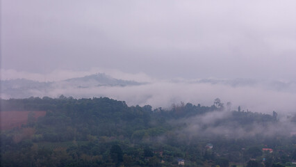 Aerial of Village in rain cloud cover tropical green mountain. Rainy season. Misty cover green...