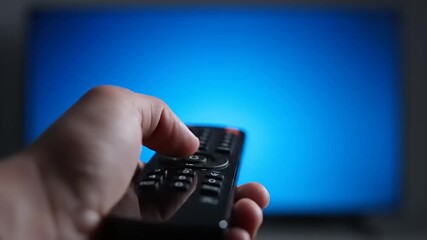 Close-up of a hand pressing a button on a TV remote control