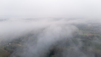 Aerial of Village in rain cloud cover tropical green mountain. Rainy season. Misty cover green forest. beautiful green village