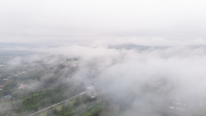 Aerial of Village in rain cloud cover tropical green mountain. Rainy season. Misty cover green forest. beautiful green village