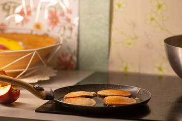 In a cozy kitchen, a wellused frying pan holds four golden pancakes stacked high, surrounded by...