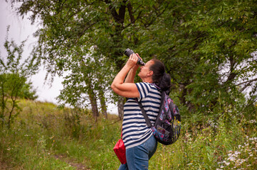 Tourism summer vacation. Hobby and leisure. Woman backpack tourist hold binoculars. Observing nature. Woman explore environment. Woman ornithology expedition in forest