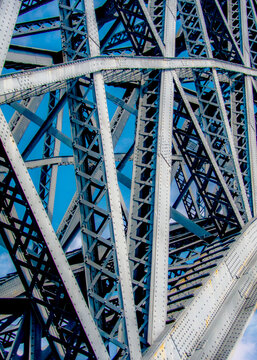 A low-angle shot of a bridge's metal structure against a blue sky.