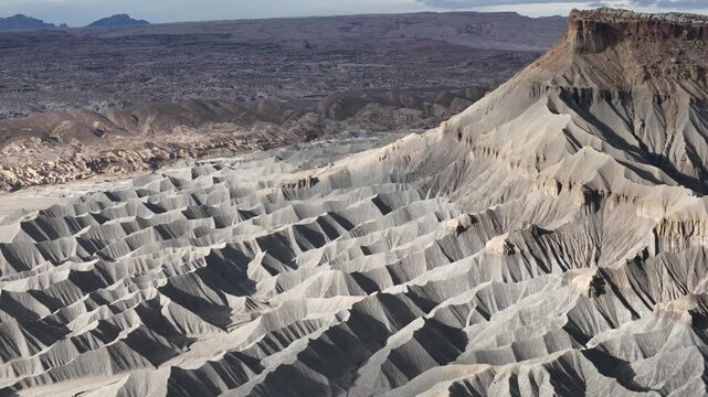 Aerial Shot of Grey Sandstone Hills Under Butte Rock Formation in Dry Desert Landscape