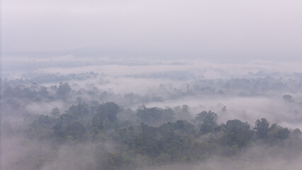 Aerial of Village in rain cloud cover tropical green mountain. Rainy season. Misty cover green forest. beautiful green village