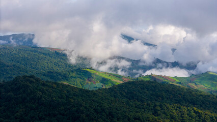 Aerial of Village in rain cloud cover tropical green mountain. Rainy season. Misty cover green forest. beautiful green village